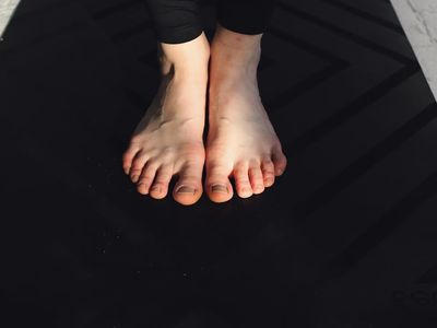 Close-up on feet maintaining balance on a yoga mat.